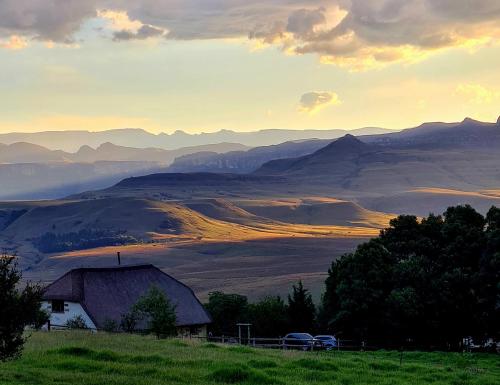 a barn on a hill with mountains in the background at Berghouse and Cottages in Langkloof