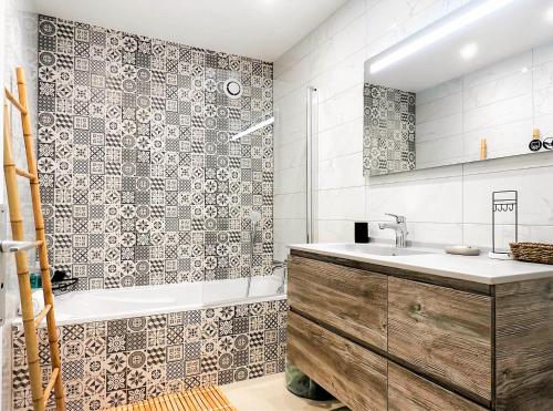 een badkamer met een wastafel, een bad en een spiegel bij Marquis proche du centre ville in Annecy