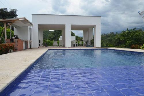 サン・ヘロニモにあるUn paraíso a 30 minutos de Medellín.の家の前の青い水の大きなスイミングプール