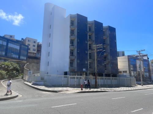 um edifício alto com uma cerca ao lado de uma rua em Apartamento em Amaralina em Salvador