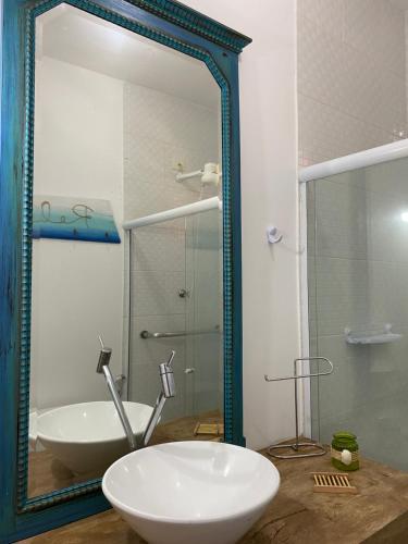 a bathroom with a mirror and a sink and a tub at Casa em condomínio a 500m da praia de Pernambuco ideal para família in Guarujá