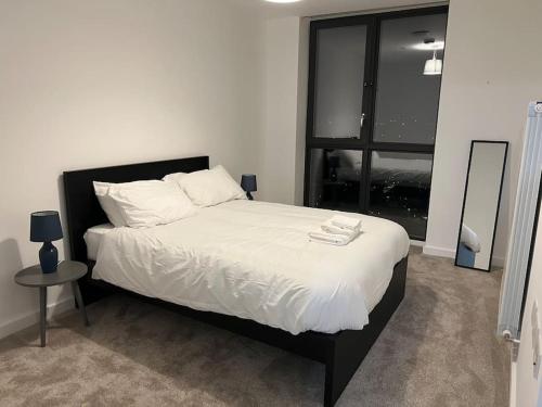 a bedroom with a bed with white sheets and a window at East London penthouse views 2bd in Barking