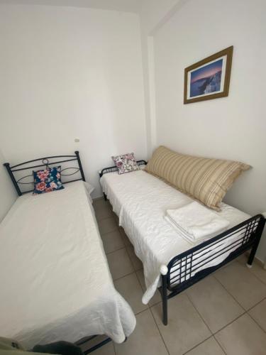 two beds in a room with white walls at AEOLOS Apartments in Akrotiri
