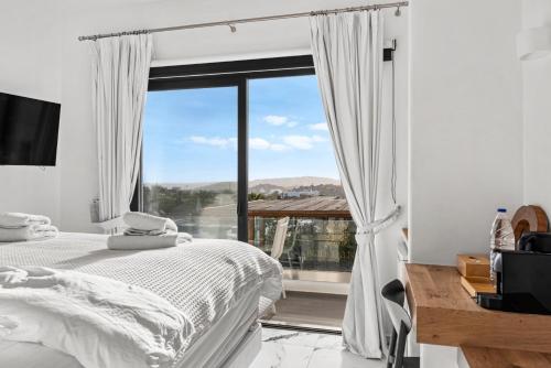 a bedroom with a bed and a large window at Bianco a Nero Mykonos in Mýkonos City
