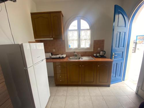 a kitchen with brown cabinets and a white refrigerator at AEOLOS Apartments in Akrotiri