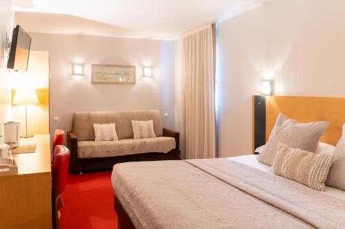 a hotel room with a bed and a chair at The Originals City, Hôtel Le Pavillon, Béziers Est in Béziers