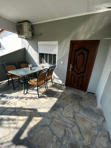 a patio with a table and chairs and a wooden door at Maison de roche 2 in Nea Kalikratia