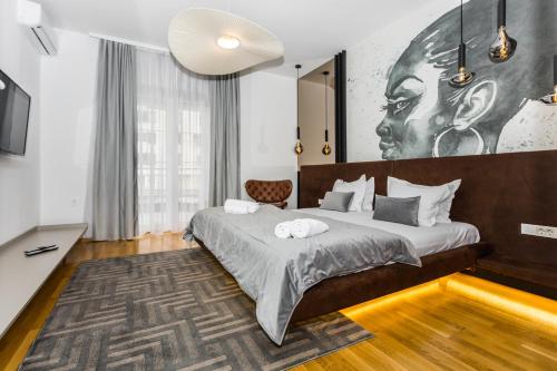 a bedroom with a bed with a large painting on the wall at Art of Living Luxury suite one in Sarajevo