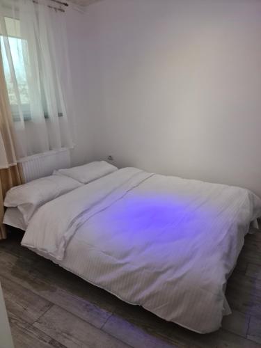 a bedroom with a white bed with a purple comforter at APARTAMENT IN CENTRU in Oradea