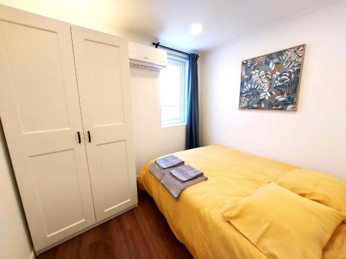 a small bedroom with a yellow bed and a window at Ritta´s House - Covilhã in Covilhã