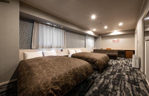 広島市にあるHotel Legitのベッド2台とソファが備わるホテルルームです。