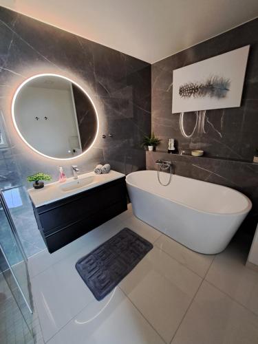 a bathroom with a tub and a sink and a mirror at Bergen sunrise Apartment - self check in - Free Parking in Bergen