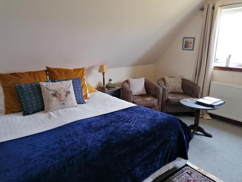 a bedroom with a large bed with a blue blanket at Balmoral Skye in Portree