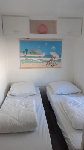 - 2 lits dans une chambre avec une photo sur le mur dans l'établissement Mobil-Home 6 Personnes, à Saint-Pair-sur-Mer