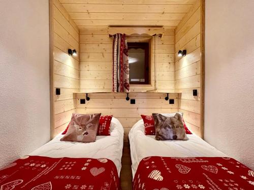two beds in a room with wooden walls and a mirror at Club Alpina - Champagny-en-Vanoise in Champagny-en-Vanoise