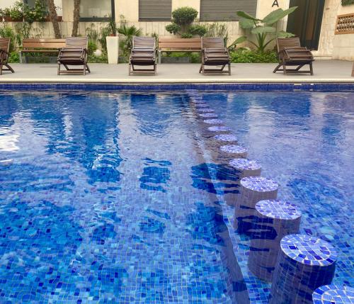 a swimming pool with chairs and blue tiles on it at Appartement les pieds dans l'eau in Mohammedia