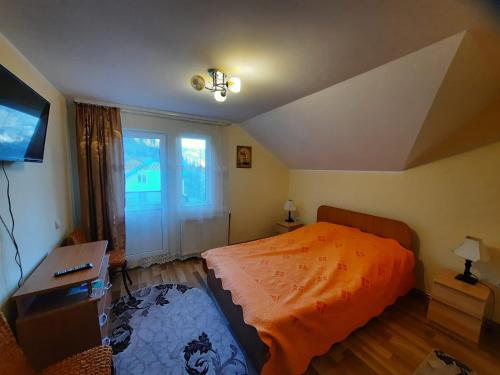 a bedroom with a bed and a desk and a window at Casa Aurici Vatra Dornei in Vatra Dornei