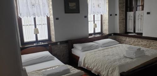 two beds in a room with two windows at Silver Hill Guesthouse in Gjirokastër