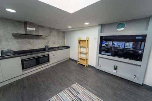 a large kitchen with a large tv and a counter at STAY SA Equipped Studios 10 mins from City centre and next to UOB! in Birmingham