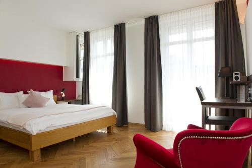 a hotel room with a bed and a red chair at Boutique Hotel NI-MO in Zürich