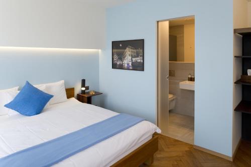 a bedroom with a white bed and a bathroom at Boutique Hotel NI-MO in Zürich
