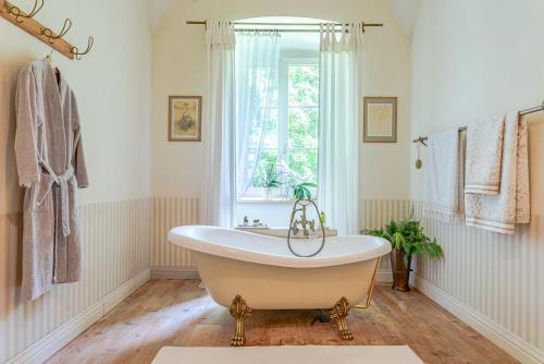 a bath tub in a bathroom with a window at Svastics kúria in Szentgáloskér