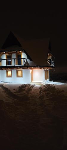 a house lit up at night in the snow at NOWA CHATA in Bustryk