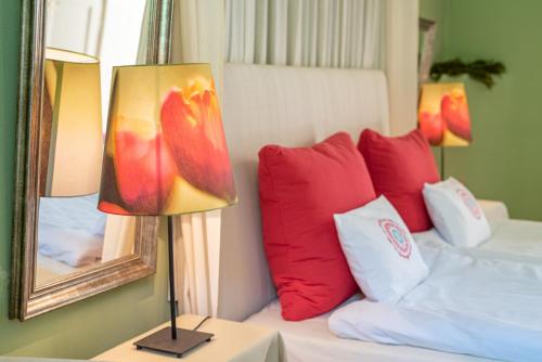a bedroom with a bed with red pillows and a lamp at Svastics kúria in Szentgáloskér