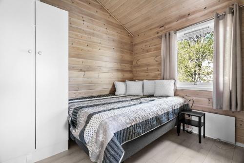 1 dormitorio con 1 cama en una pared de madera en Krokane Camping Florø en Florø