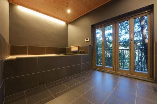 - une grande salle de bains avec une grande fenêtre et du carrelage dans l'établissement けやき坂, à Ogi