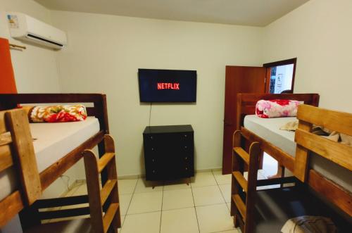 a room with two bunk beds and a tv at Casa Executiva Orla Morena in Campo Grande