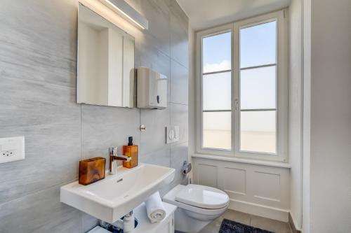 a white bathroom with a sink and a toilet at The 5 Continents II by Stay Swiss in Porrentruy