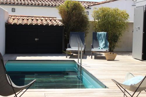 une piscine dans une cour avec des chaises et une maison dans l'établissement Résidence MV Lodge, à La Couarde-sur-Mer