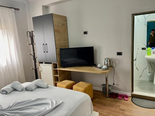 een slaapkamer met een bed en een bureau met een televisie bij Central room private entry and bathroom in Tirana