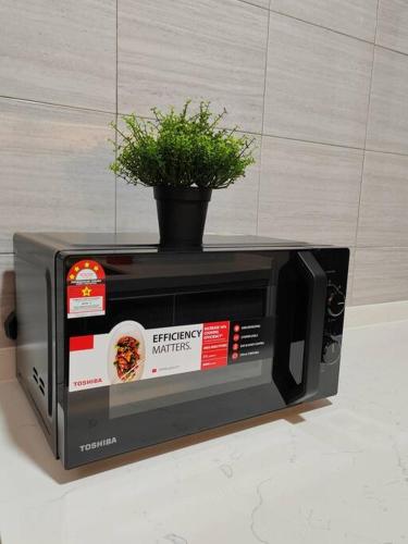 a microwave with a plant on top of it at Symphony Tower 3BR High Floor 100mbps Wi-Fi Netflix in Cheras