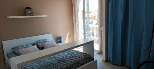 Cette chambre comprend un lit avec un rideau bleu et une fenêtre. dans l'établissement Villa Semaphore, à Salin-de-Giraud