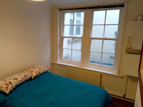 Un dormitorio con una cama azul y una ventana en Lovely 1-bedroom flat within minutes from the beach!, en Bexhill-on-Sea