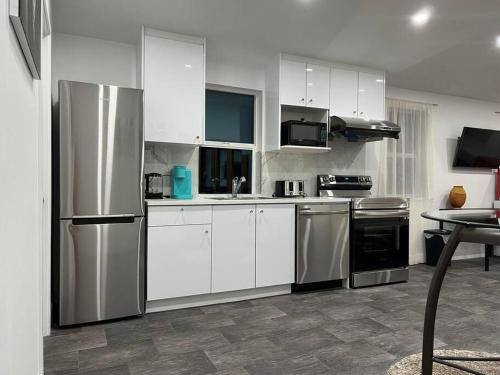 a kitchen with white cabinets and stainless steel appliances at The Lions Self Contained Suite, Shared Pool, Hot Tub, Views in North Vancouver