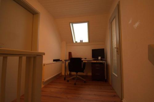 ein Büro mit einem Schreibtisch mit einem Computer und einem Fenster in der Unterkunft Haus Maria in Ratzeburg