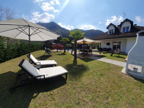 un cortile con due sedie a sdraio e un ombrellone di Villa Mariel Lago Maggiore luxury Suite & Wellness a Gravellona Toce