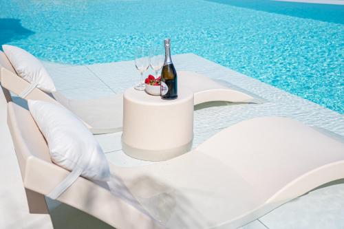 a table with a bottle of wine and chairs next to a pool at Gatsby Rhodes-Brand New Seaview Villa in Asgourou