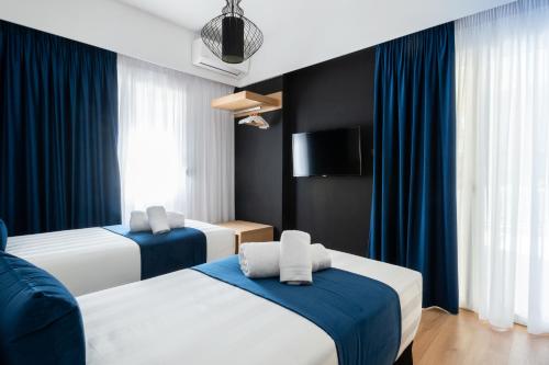 a hotel room with two beds with blue curtains at Acropolis Exclusive Apartment in Athens