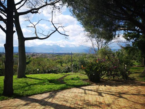 a brick walkway with trees and a view of mountains at Saja Country House in Acireale