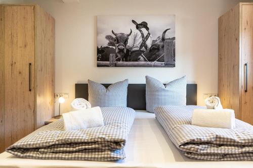 ein Schlafzimmer mit 2 Betten und ein Bild von Kühen in der Unterkunft Wetterstein in Oberstaufen