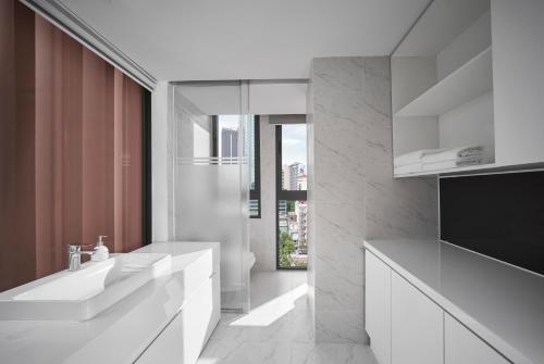 baño blanco con 2 lavabos y ventana grande en M Village Tôn Thất Đạm en Ho Chi Minh