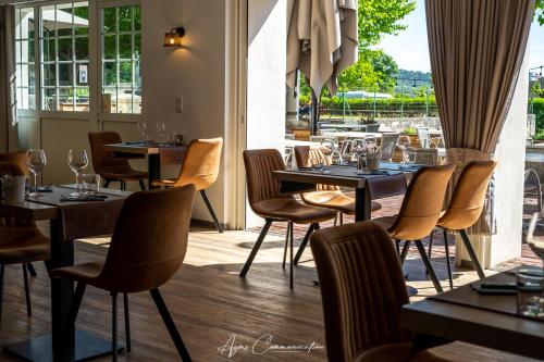 a restaurant with tables and chairs and a window at Logis du Champ De Mars in Puy-Saint-Martin
