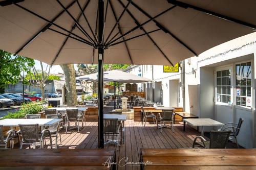 an outdoor patio with tables and chairs and umbrellas at Logis du Champ De Mars in Puy-Saint-Martin