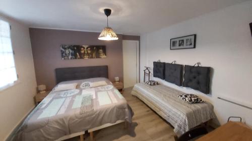 1 dormitorio con 2 camas y lámpara de araña en Le Mas d'Evlie, en Aubin