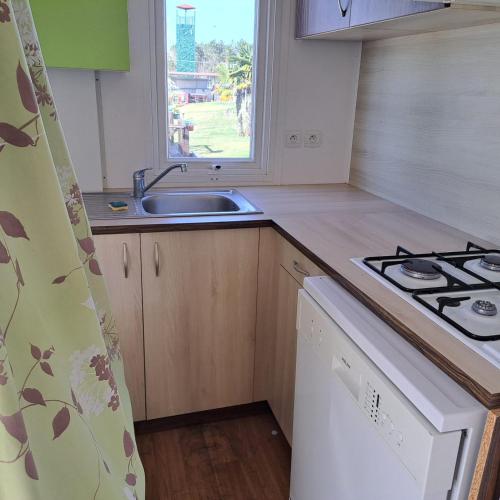 a kitchen with a sink and a stove and a window at Bungalows Land'shause in Pataias