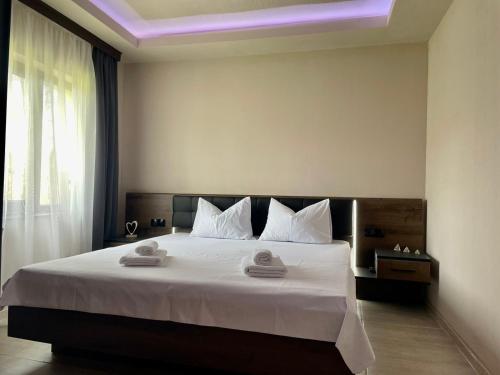 1 dormitorio con 1 cama grande con sábanas y almohadas blancas en Къща за гости ЕМ Парадайс en Tserova Koriya